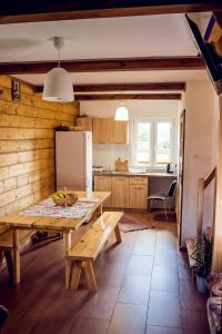 a kitchen with a wooden table and a refrigerator at Chata Białowieska Pod Bocianem in Hajnówka