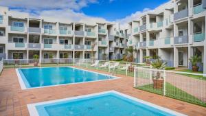 a swimming pool in front of a apartment building at Marea Fuerteventura Home in Corralejo