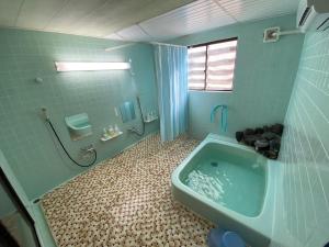Baño azul con bañera y lavamanos en Nozawa Dream Central, en Nozawa Onsen