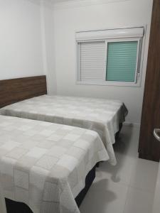 2 camas en una habitación blanca con ventana en Lindo Apto Em Bombinhas, en Bombinhas