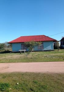 una casa azul con techo rojo junto a un camino de tierra en Palafito, en Aguas Dulces