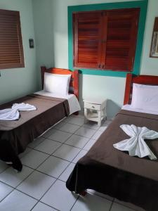 - une chambre avec 2 lits et des serviettes dans l'établissement Casa verde milagres, à Maceió