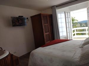 1 dormitorio con cama y ventana grande en Pousada Miraggio, en Campos do Jordão