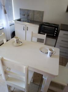 a white table with two cups on it in a kitchen at Spacious 1bed + braai 13km to Paternoster beach in Vredenburg