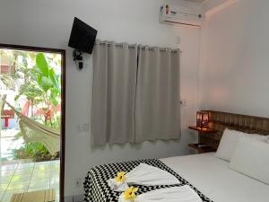 1 dormitorio con 1 cama con cortina y ventana en Pousada do Mineiro, en Trancoso