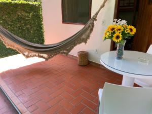a hammock on a patio with a table and flowers at Pousada do Mineiro in Trancoso
