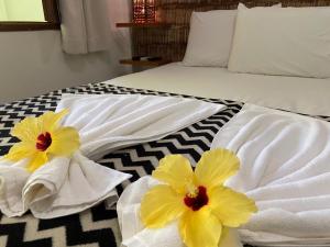 a bed with white towels and yellow flowers on it at Pousada do Mineiro in Trancoso