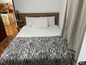 a bed in a room with a zebra print blanket at Pousada do Mineiro in Trancoso