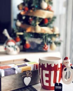 Mavrovo Twins Apartment في مافروفو: وجود كوب قهوة على طاولة مع شجرة عيد الميلاد في الخلفية