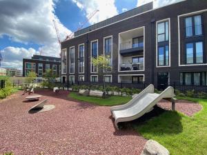 une aire de jeux en face d'un bâtiment avec toboggan dans l'établissement Olympic Family Home, With Own Garden Bliss, à Londres