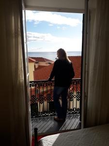 Una donna in piedi su un balcone che guarda fuori dalla porta di Pensao Residencial Mirasol a Funchal