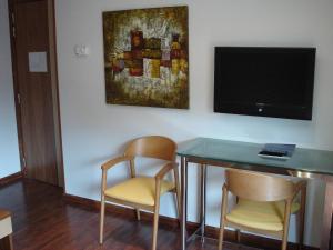 une chambre avec une table, deux chaises et une télévision dans l'établissement Hotel Iris, à Granollers