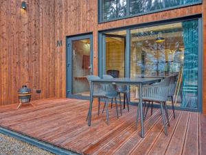 een houten terras met een tafel en stoelen erop bij Tleń Lodge - domy całoroczne z jacuzzi in Tleń