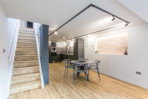 a dining room with a table and a staircase at The Brewery Apartments in Stockport