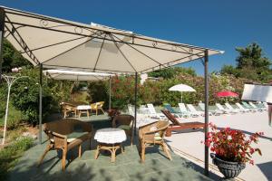 un patio con sillas, mesas y una sombrilla en Villa Anna, en Savudrija