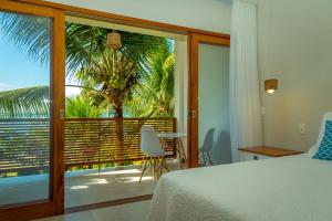 a bedroom with a bed and a balcony with a palm tree at Pousada Catarina in Paraty
