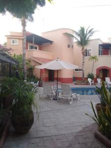 a patio with chairs and an umbrella and a pool at Coco Cabanas Loreto in Loreto