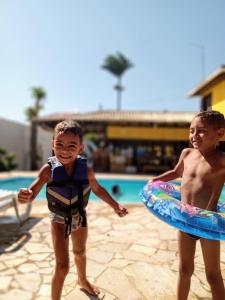 dos jóvenes parados junto a una piscina en Pousada Gente Bonita João Fernandes, en Búzios