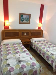 duas camas num pequeno quarto com luzes vermelhas em Apartamentos colon y bungalows em Los Quemados