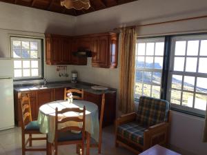 een keuken met een tafel, stoelen en ramen bij Apartamentos colon y bungalows in Los Quemados