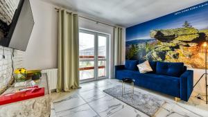 uma sala de estar com um sofá azul e uma janela em Apartament Sępia Góra Premium z Sauną - 5D Apartamenty em Świeradów-Zdrój