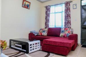 un soggiorno con divano rosso e sedia di Rubistones a Naivasha