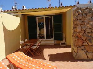 a patio with a table and chairs and a stone wall at Apartamento las Siete Palmeras in Cala en Blanes