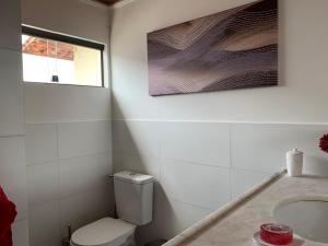 La salle de bains blanche est pourvue de toilettes et d'un lavabo. dans l'établissement Taverna do Paraiso, à Janga
