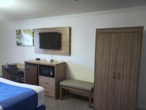 a hotel room with a bed and a cabinet and a tv at Exchange Club Motel in Beatty