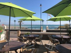 a patio with tables and chairs with green umbrellas at De L'Etang in Saint Helier Jersey