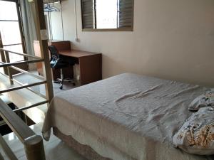 a bedroom with a bed and a desk and a chair at Loft em Botucatu prox unesp rubiao jr in Botucatu