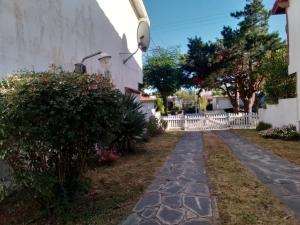 un camino de piedra frente a una casa con una valla blanca en Casa en Las Toninas Buenos Aires en Las Toninas