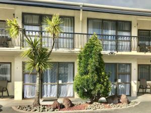 een gebouw met twee palmbomen ervoor bij Motel Villa Del Rio in Whangarei