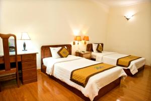 a hotel room with two beds and a desk at Bamboo Green Riverside Hotel in Danang