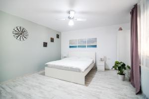 Dormitorio blanco con cama y reloj en la pared en Transylvania Guest House, en Brasov