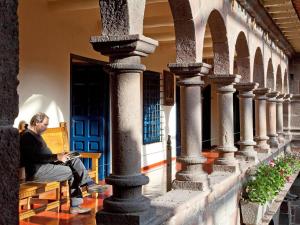 un hombre sentado en un banco en un edificio con un libro en Novotel Cusco en Cuzco