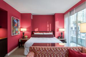 - une chambre rouge avec un lit et un canapé dans l'établissement OPUS Vancouver, à Vancouver