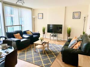 sala de estar con sofá de cuero negro y TV en Smartrips Apartments - The Hub, en Milton Keynes