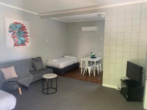 a living room with a couch and a bed and a table at Hello Adelaide Motel and Apartments in Adelaide