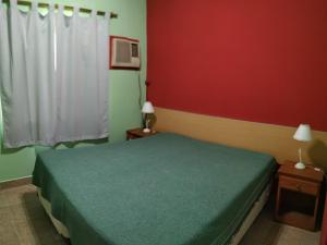a bedroom with a green bed and red walls at Hotel de Campo con Piscina y Cabañas- Ideal Relax en Concordia in Concordia +16 photos