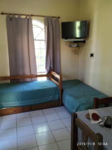 um pequeno quarto com duas camas e uma televisão em Hotel de Campo em Concordia