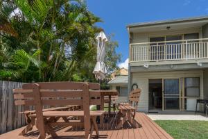 a patio with a wooden bench and an umbrella at Pandanus Palms Holiday Resort in Point Lookout