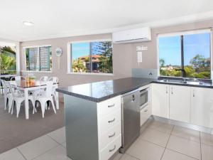 a kitchen with white cabinets and a dining room with a table at Broadwater Quays 5 in Mooloolaba