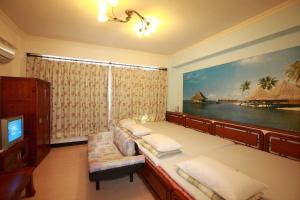 una camera con due letti e una TV e un quadro di Cruise Homestay a Città di Hualien