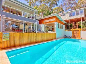 une maison avec une piscine en face d'une maison dans l'établissement Tranquil Beach House with Outdoor Decks and Pool, à Avoca Beach