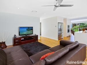 een woonkamer met een bruine leren bank en een flatscreen-tv bij Tranquil Beach House with Outdoor Decks and Pool in Avoca Beach