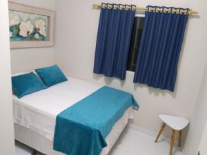 um quarto com uma cama com cortinas azuis e uma janela em Flor de Peroba Flats #2 Azul - Maragogi - AL em Maragogi