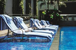 a row of blue and white chairs sitting on top of a pool at Oasia Resort Sentosa by Far East Hospitality in Singapore