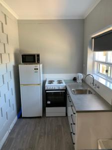 a kitchen with a white refrigerator and a sink at Hello Adelaide Motel and Apartments in Adelaide