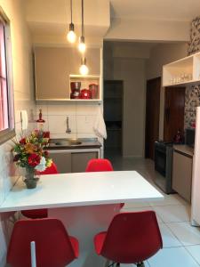 apartamento 04 super luxo, com garagem, vila-alta Crato في كراتو: مطبخ مع طاولة بيضاء وكراسي حمراء